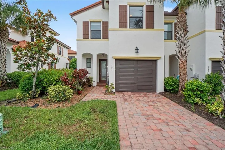 Stucco exterior with a tile roof, decorative shutters, a single-car garage, and a brick paver driveway