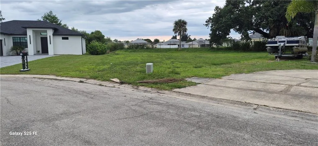 Expansive cleared lot with established grass, featuring existing curb cut for driveway access