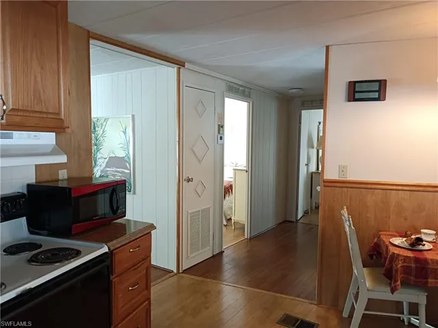 Kitchen with hardwood / wood-style floors, white electric range oven, and range hood