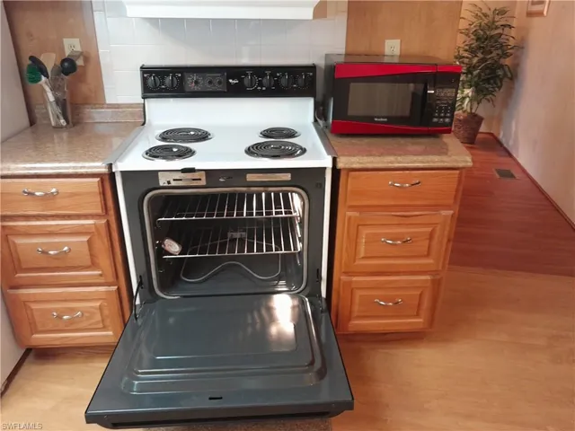 Kitchen featuring light wood-type flooring, backsplash, and electric stove