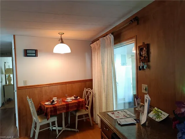 Dining area with dark hardwood / wood-style flooring and wooden walls