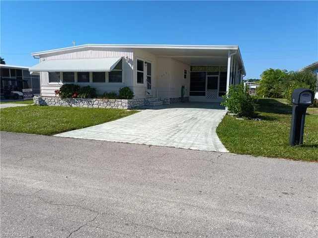 Manufactured / mobile home with a front lawn and a carport