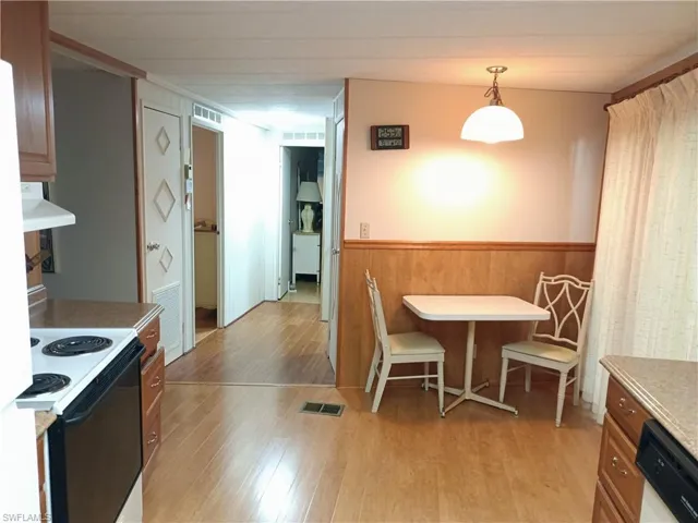 Kitchen featuring light wood-type flooring, white electric range oven, pendant lighting, black dishwasher, and custom range hood