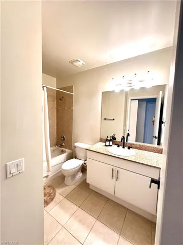 Full bathroom featuring tile floors, shower / bath combination with curtain, oversized vanity, and toilet