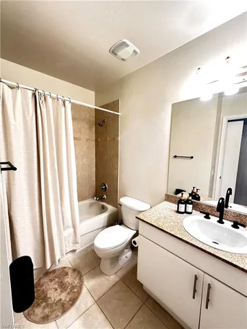Full bathroom featuring tile flooring, oversized vanity, toilet, and shower / bath combo