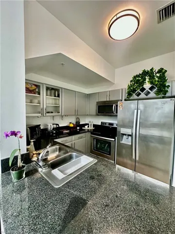 Kitchen with stainless steel appliances, gray cabinetry, and sink