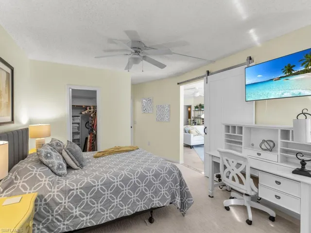 Carpeted bedroom featuring a textured ceiling, a barn door, ceiling fan, a closet, and a spacious closet