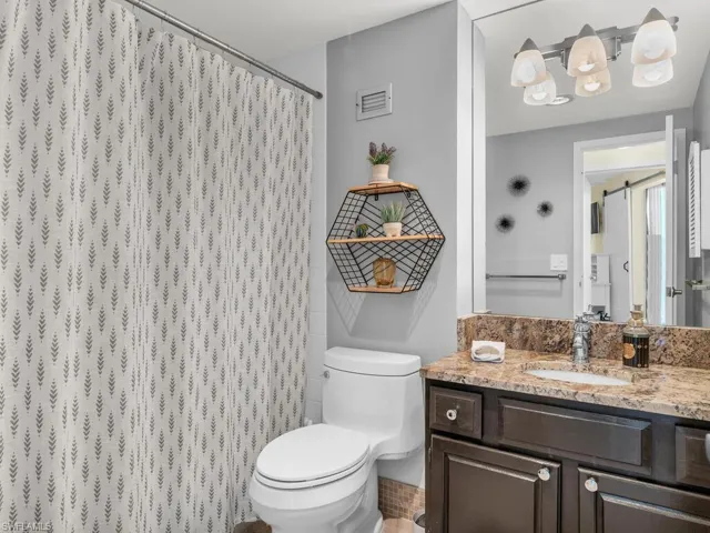 Bathroom with a shower with curtain, vanity, and toilet