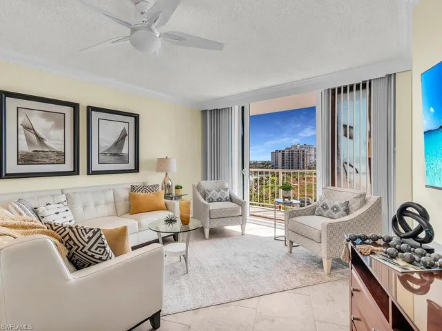 Living room with a textured ceiling, ceiling fan, and light tile patterned flooring