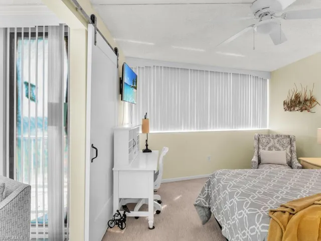 Carpeted bedroom with a barn door, ceiling fan, and a textured ceiling