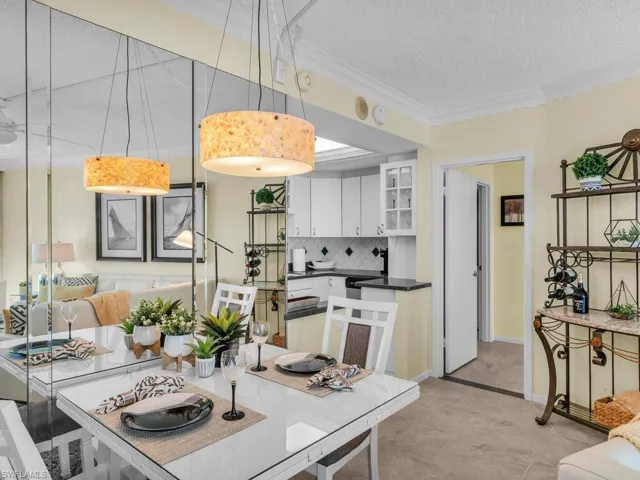 Kitchen with white cabinetry, tasteful backsplash, ornamental molding, a textured ceiling, and hanging light fixtures