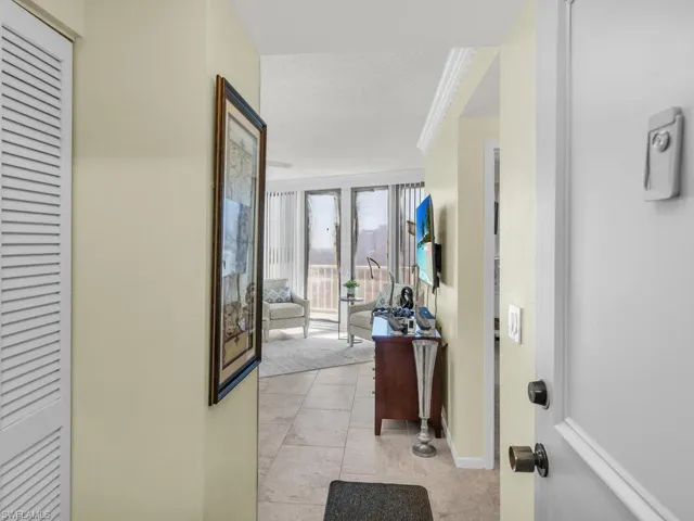 Corridor featuring a textured ceiling, light tile patterned floors, and crown molding