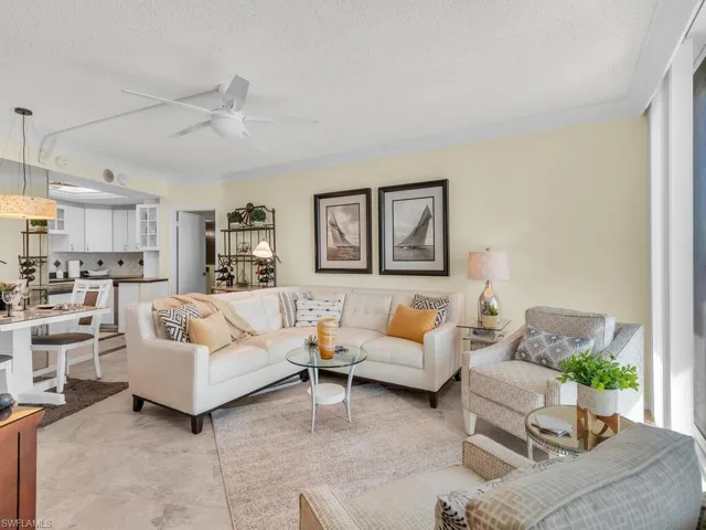 Tiled living room featuring a textured ceiling, ceiling fan, and crown molding