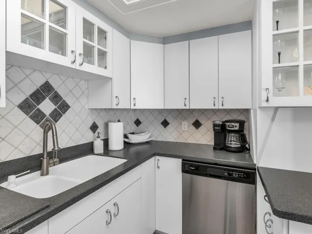 Kitchen featuring dishwasher, backsplash, and white cabinets