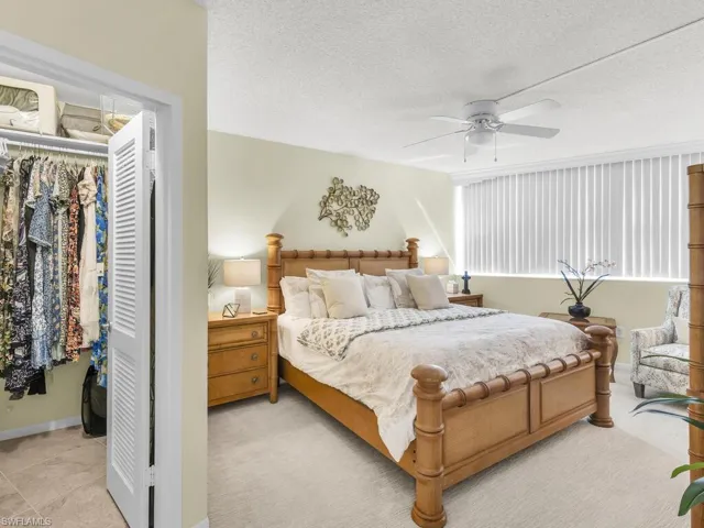 Bedroom with a closet, a textured ceiling, light carpet, and ceiling fan
