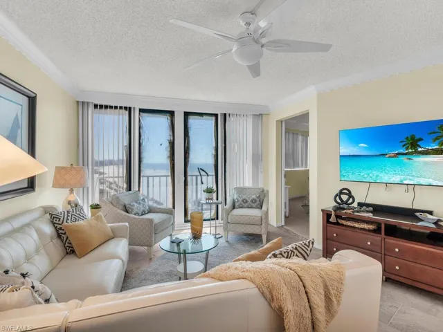 Living room with ornamental molding, a textured ceiling, and ceiling fan