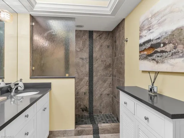 Bathroom featuring vanity, tiled shower, and a raised ceiling
