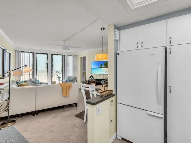 Kitchen featuring white refrigerator, white cabinets, hanging light fixtures, a textured ceiling, and ceiling fan