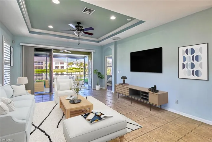 Tiled living room featuring a tray ceiling and ceiling fan