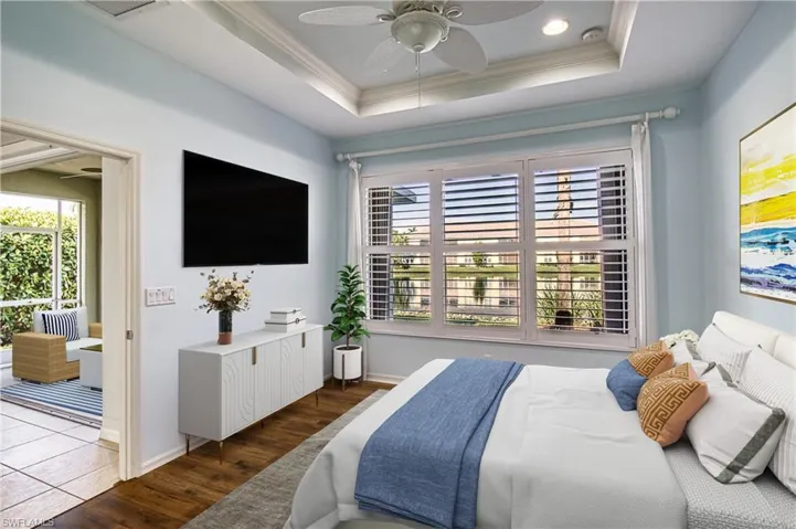 Bedroom with multiple windows, a raised ceiling, dark hardwood / wood-style flooring, and ceiling fan