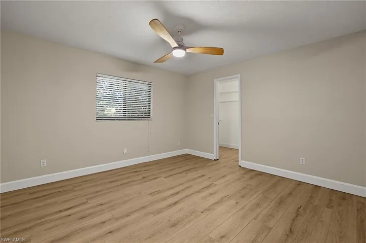 Unfurnished room with baseboards, light wood-type flooring, ceiling fan, and a textured ceiling