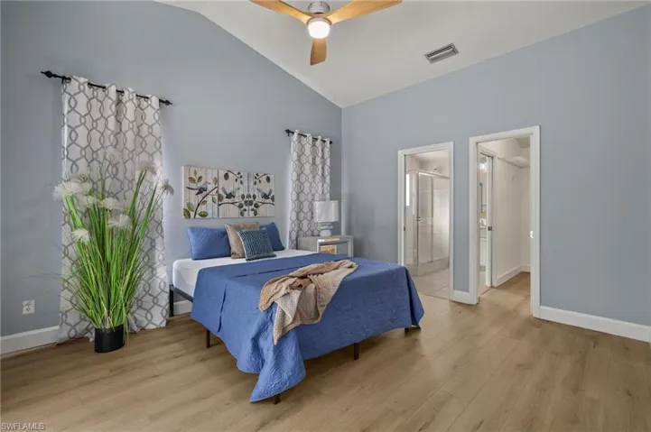 Bedroom featuring wood finished floors, baseboards, vaulted ceiling, and visible vents
