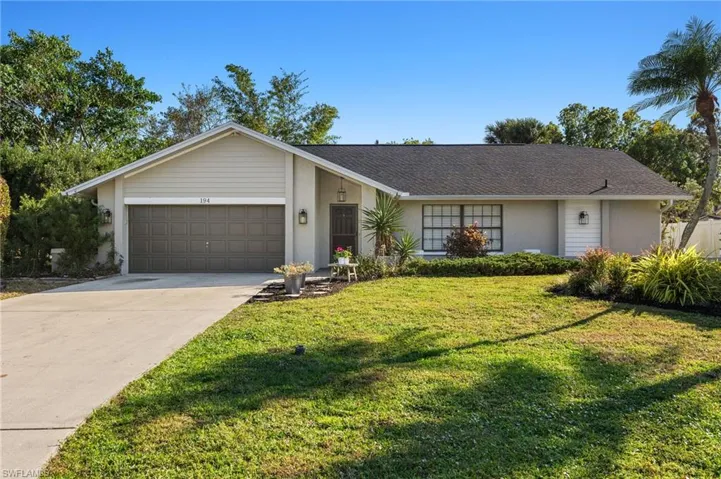 View of front facade with stucco siding, driveway, a garage, and a front yard