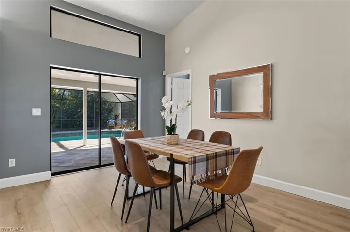 Dining area with baseboards, a towering ceiling, and light wood-style floors