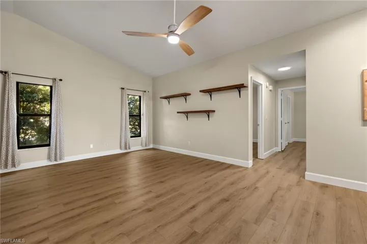 Unfurnished living room with a ceiling fan, lofted ceiling, baseboards, and light wood finished floors