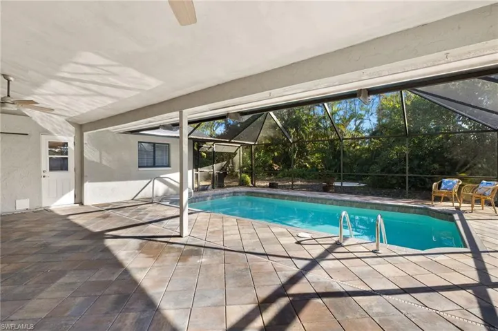 Outdoor pool with a ceiling fan, a lanai, and a patio area