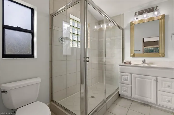Bathroom with a stall shower, toilet, tile patterned flooring, and vanity