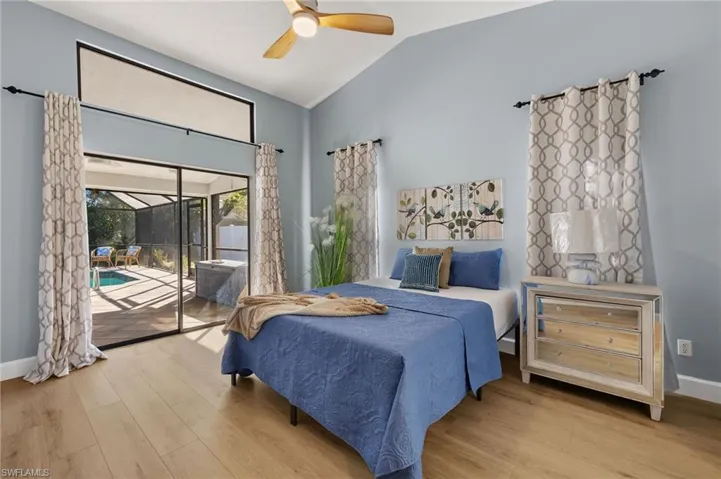 Bedroom with baseboards, vaulted ceiling, wood finished floors, and access to outside