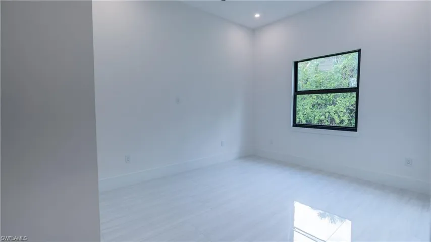 Room featuring light-toned flooring, white walls, and a black-framed window