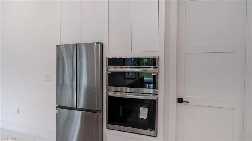 Stainless steel French door refrigerator and built-in double oven appliances integrated into white cabinetry