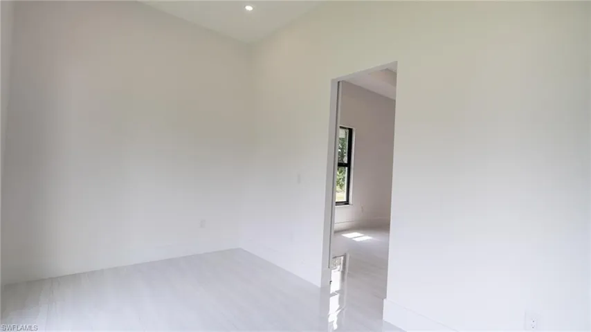 Spacious room featuring white tile flooring, recessed lighting, and a wide entryway