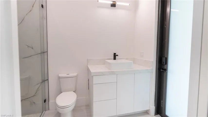 Bathroom featuring a contemporary vanity with a vessel sink, quartz countertop, and black hardware