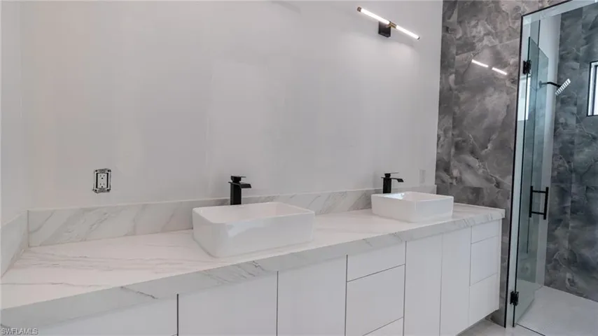 Double vanity featuring white slab-front cabinetry and a white countertop with subtle veining
