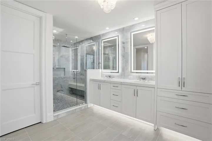 Bathroom with double vanity, a marble finish shower, light tile patterned floors, and recessed lighting