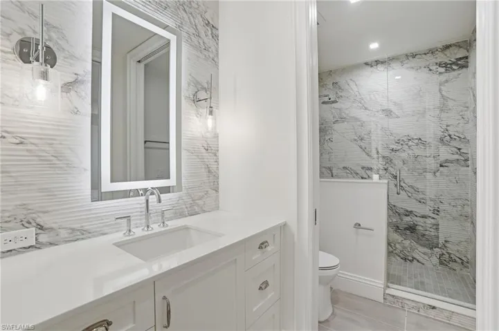 Bathroom with vanity, a stall shower, tile walls, and recessed lighting