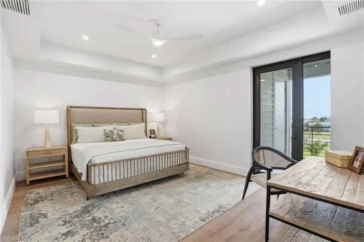Bedroom featuring light wood-type flooring, access to outside, ceiling fan, a raised ceiling, and recessed lighting