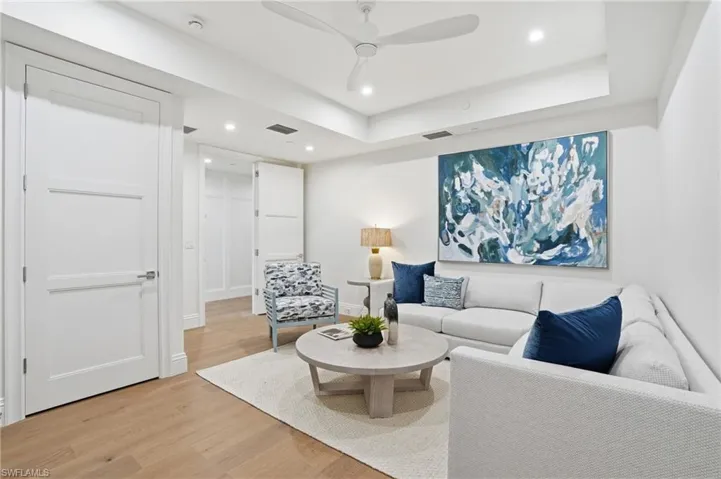 Living area featuring light wood-type flooring, recessed lighting, a ceiling fan, and a raised ceiling