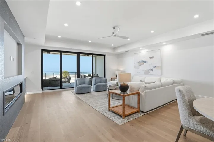 Living room featuring a ceiling fan, light wood-style floors, a water view, a raised ceiling, and recessed lighting