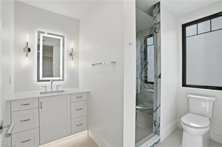 Full bath featuring vanity, a marble finish shower, and light tile patterned floors