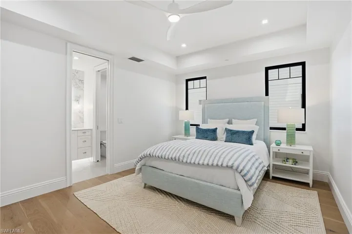 Bedroom featuring light wood-type flooring, ceiling fan, recessed lighting, and a tray ceiling