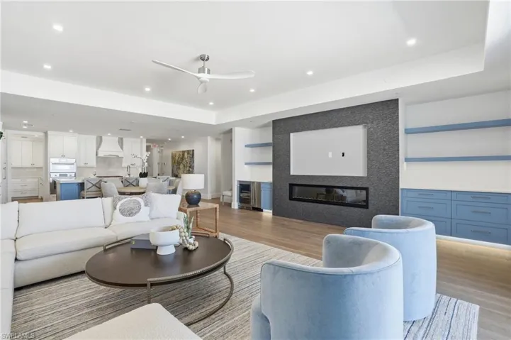 Living area with a large fireplace, ceiling fan, wood finished floors, beverage cooler, and recessed lighting