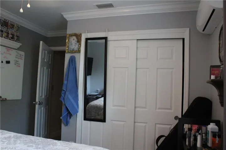 Bedroom with ornamental molding, a closet, and a wall mounted AC