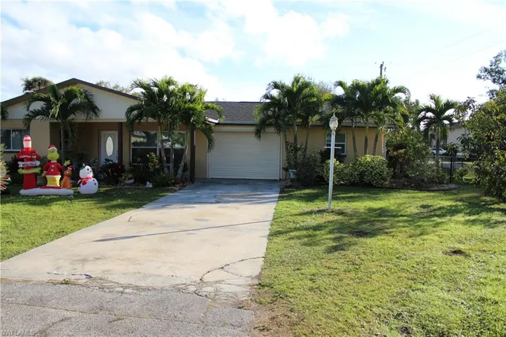 Ranch-style house featuring driveway, a front yard, and an attached garage