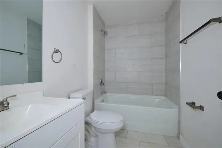 Full bathroom featuring toilet, tiled shower / bath combo, and vanity