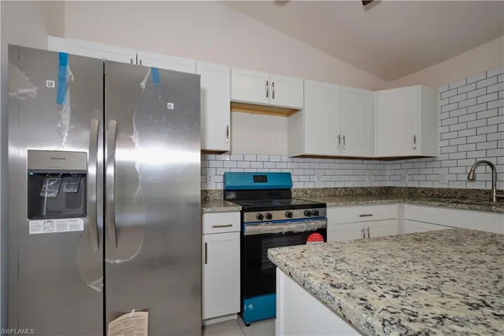 Kitchen with stainless steel appliances, white cabinets, and sink