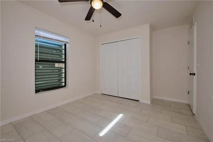 Unfurnished bedroom with ceiling fan and a closet